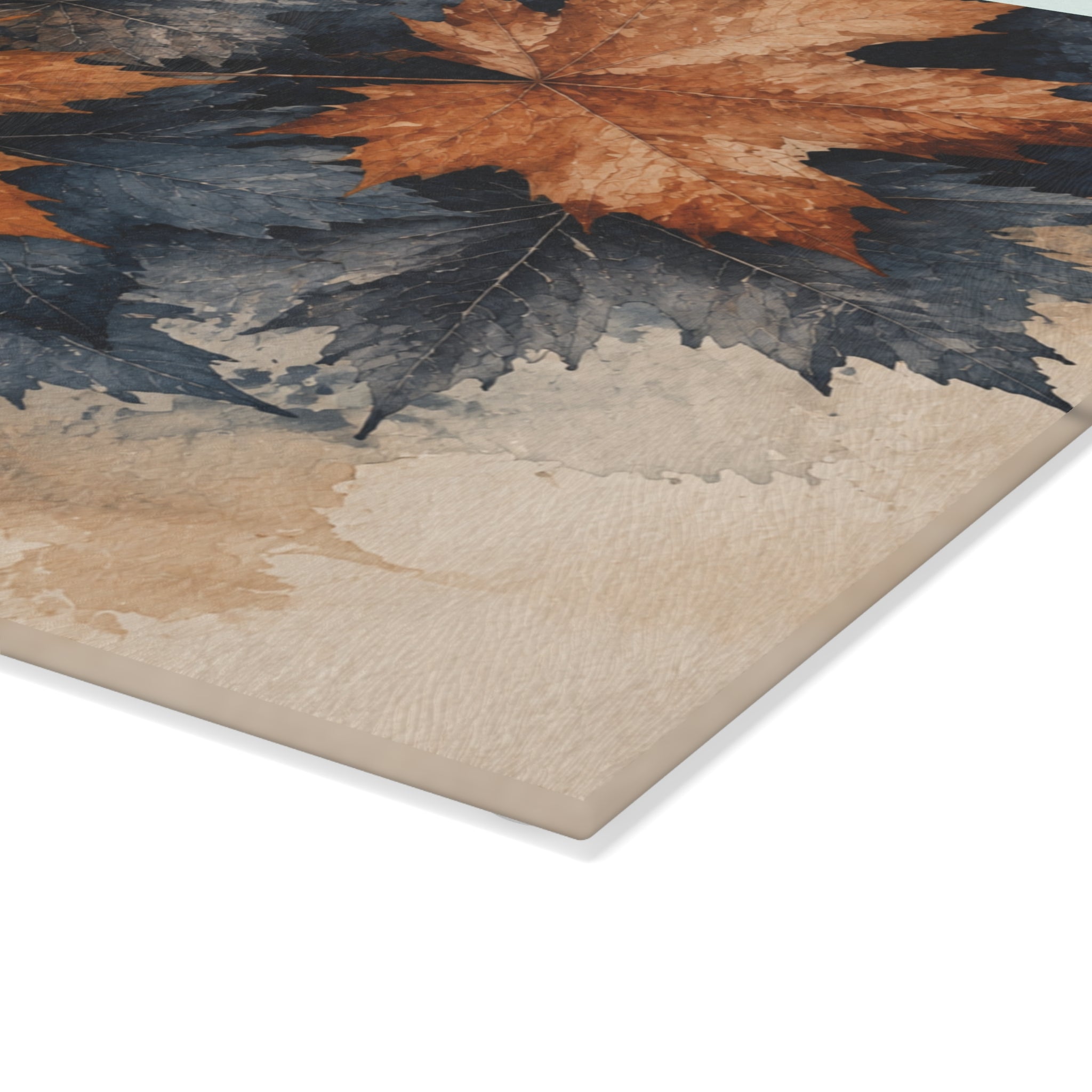 A close-up of the cutting board showing a printed autumn leaf design with orange-brown maple leaves over dark blue-gray and beige watercolor-like washes, photographed on a white background.